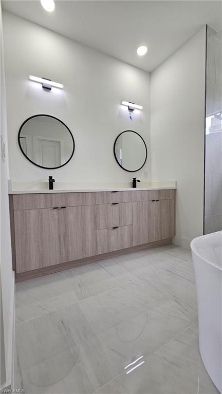 Full bath featuring a freestanding tub, double vanity, and recessed lighting