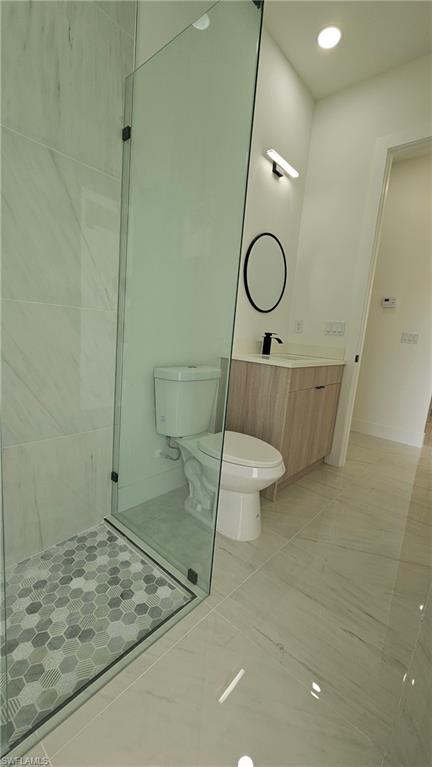 Full bath with vanity, light tile patterned flooring, recessed lighting, and a stall shower