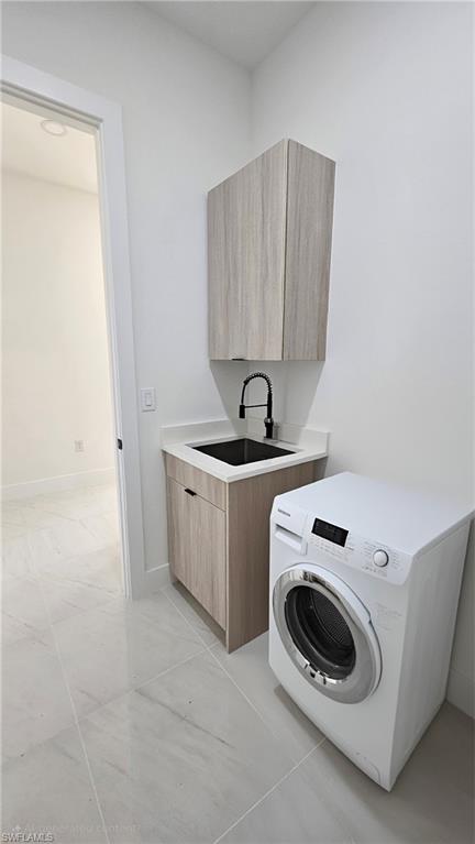 Laundry room featuring washer / dryer, cabinet space, and light tile patterned floors