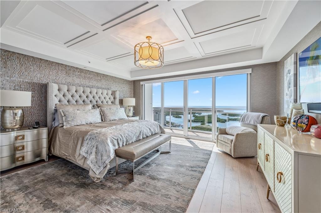 Master Bedroom featuring a water view, wallpapered walls, multiple windows, hardwood / wood-style flooring, and coffered ceiling