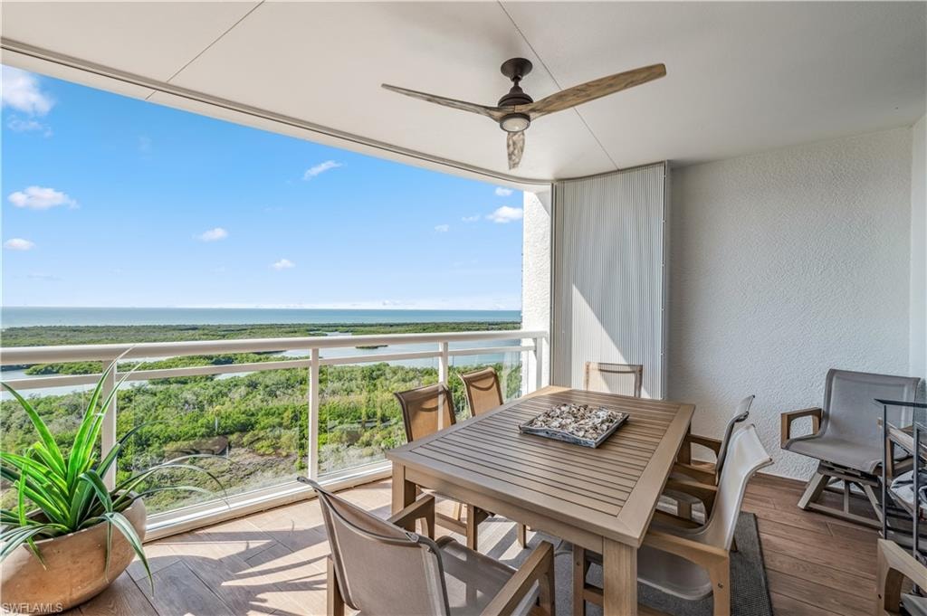 Balcony with a ceiling fan, view of water and bay, and outdoor dining area