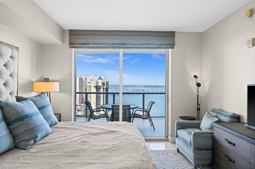 Bedroom with access to exterior, a wall of windows, and a city view