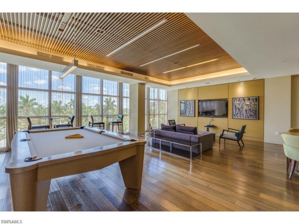 Rec room featuring a raised ceiling, pool table, wood-type flooring, and a wall of windows