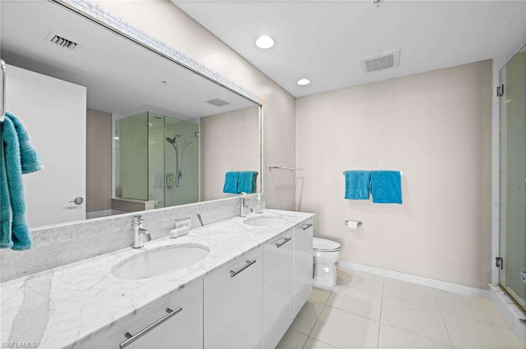 Full bathroom with double vanity, a stall shower, and recessed lighting