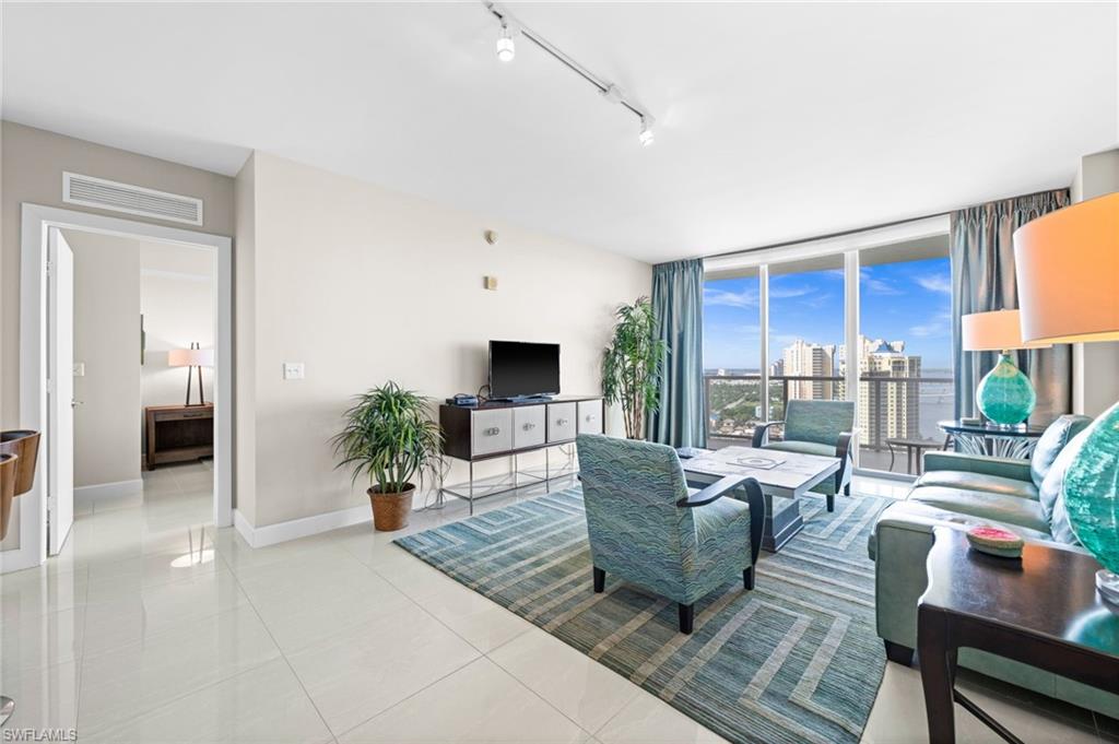 Living area featuring track lighting, light tile patterned floors, and expansive windows