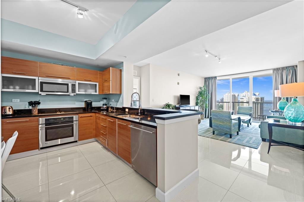Kitchen with track lighting, modern cabinets, light tile patterned flooring, appliances with stainless steel finishes, and expansive windows