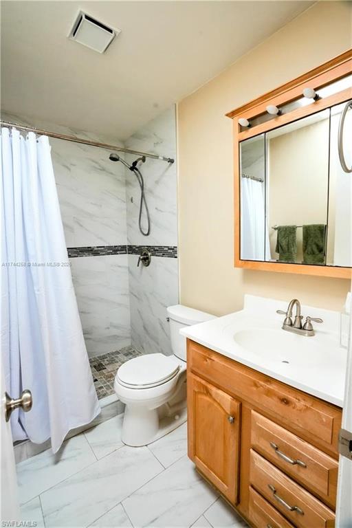 Full bathroom with vanity, a shower stall, and light marble finish floors