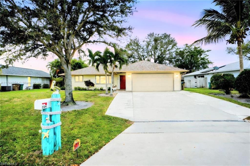 Ranch-style house featuring concrete driveway, an attached garage, a lawn, and a shingled roof
