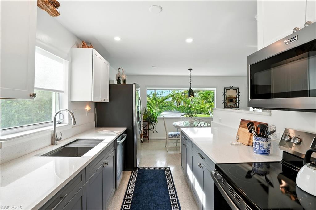Kitchen featuring stainless steel appliances, light stone countertops, decorative light fixtures, white cabinetry, and recessed lighting