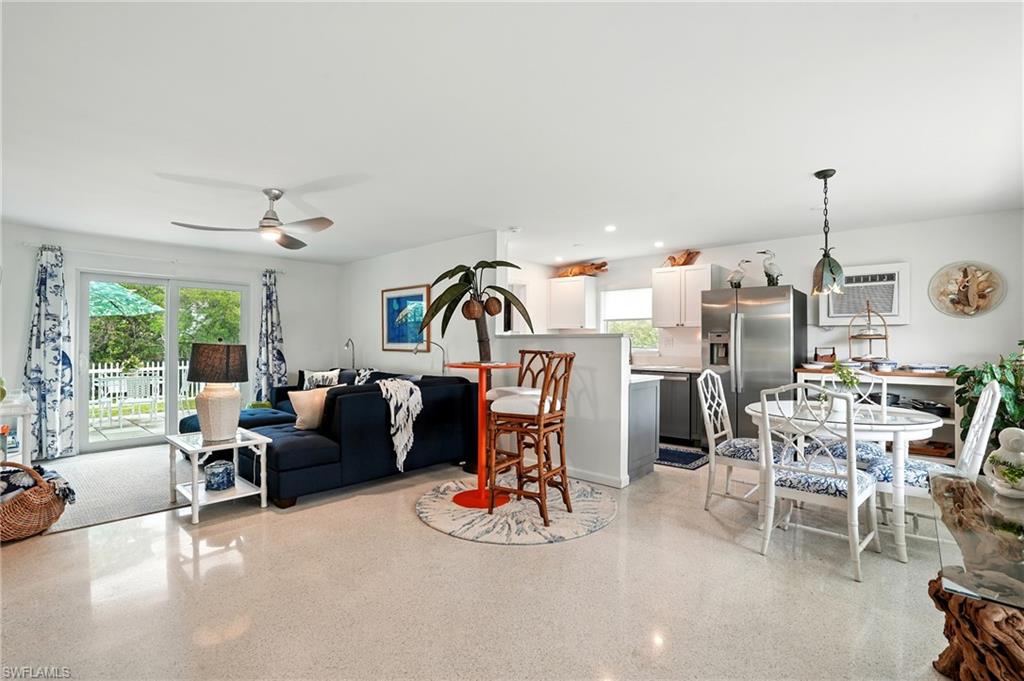 Living area featuring dark aggregate flooring, ceiling fan, recessed lighting, and a wall mounted air conditioner