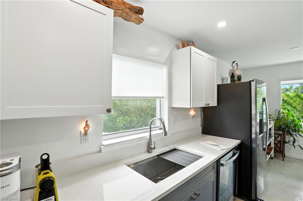 Kitchen featuring plenty of natural light, light stone countertops, dishwasher, recessed lighting, and white cabinetry