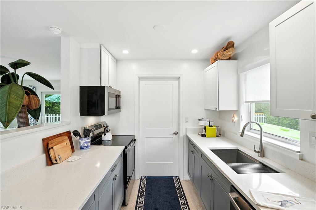 Kitchen with appliances with stainless steel finishes, light stone counters, white cabinets, recessed lighting, and gray cabinetry