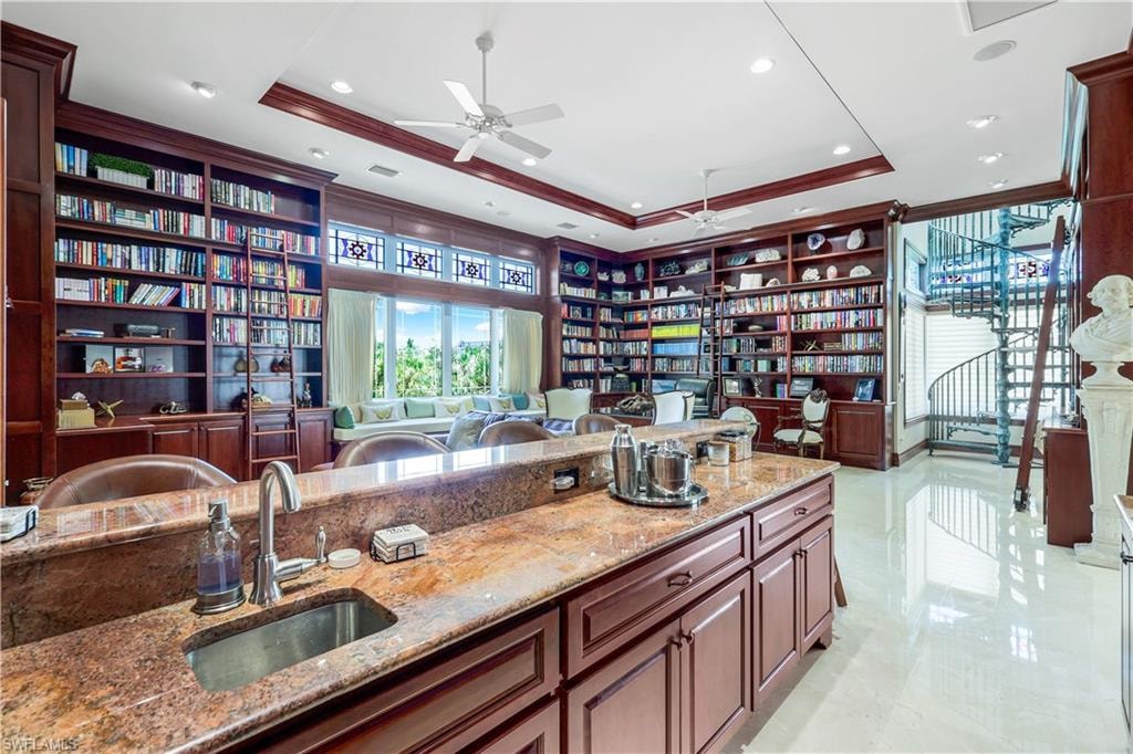 Bar area with a raised ceiling, light stone countertops, crown molding, a ceiling fan, and recessed lighting