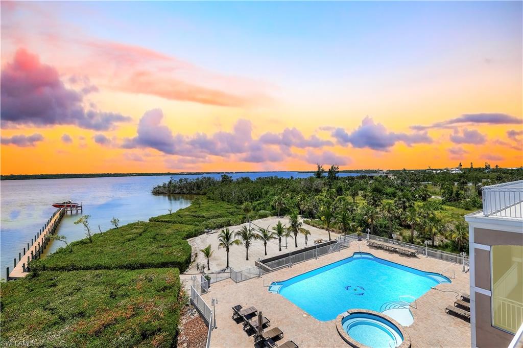 Artificially enhanced sky. View of pool featuring a water view, a patio area, and a pool with connected hot tub