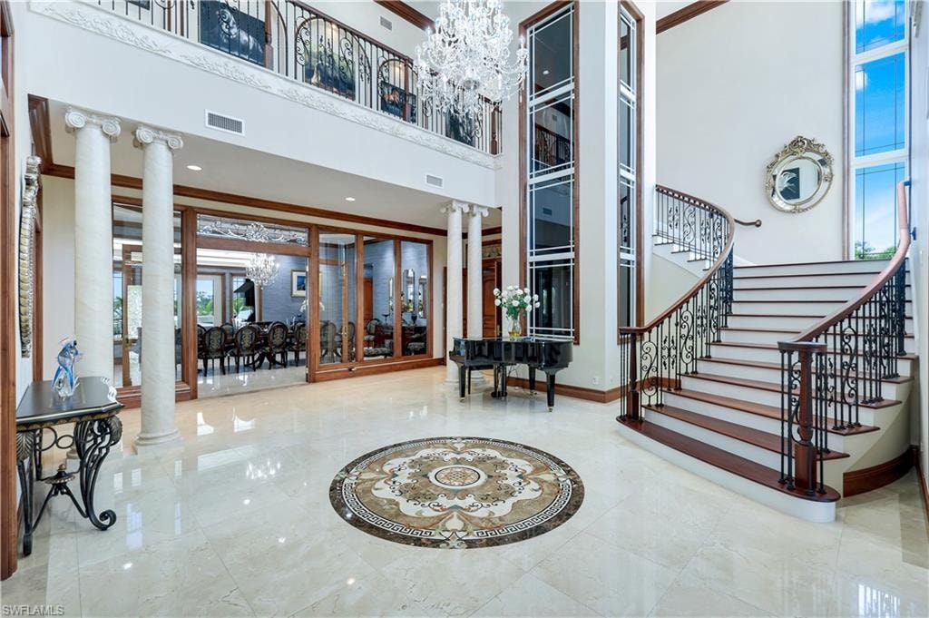 Lobby featuring a towering ceiling, ornamental molding, and stairway