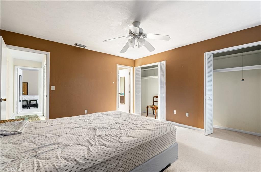 Bedroom with multiple closets, carpet flooring, and ceiling fan