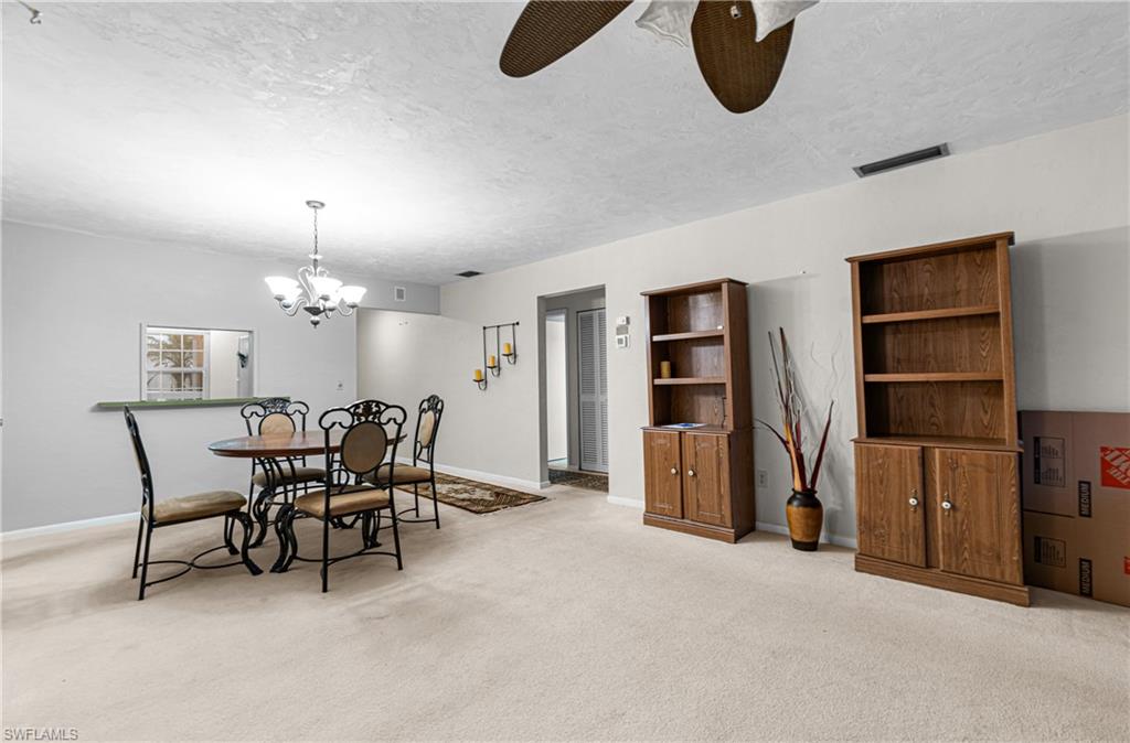 Dining space with a textured ceiling, light colored carpet, and a chandelier