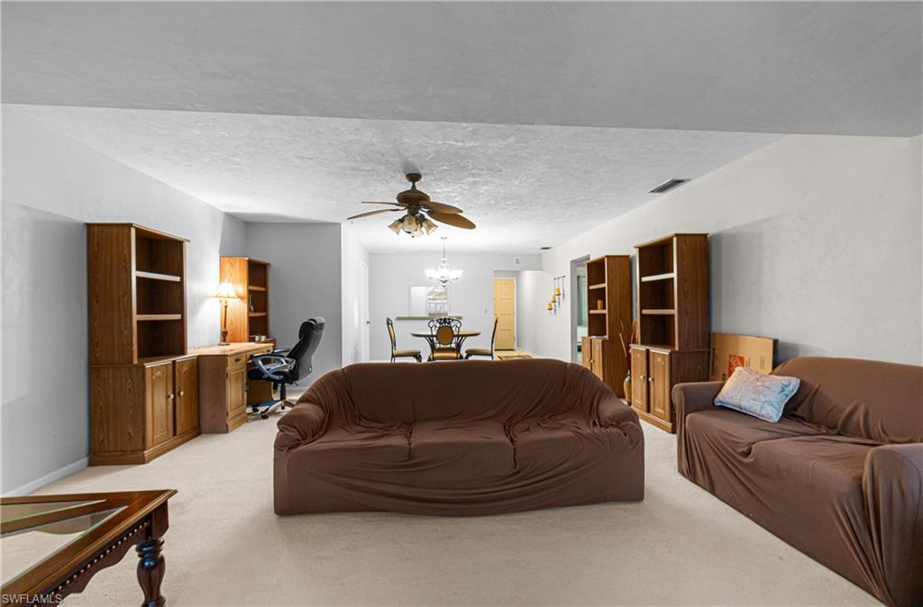 Living room featuring a desk, a textured ceiling, ceiling fan, and light carpet