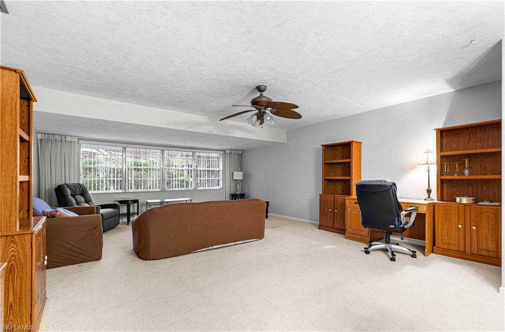 Home office with ceiling fan, light carpet, and a textured ceiling