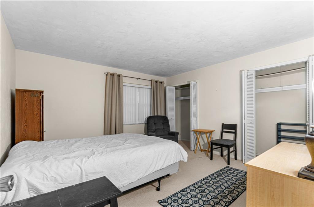 Bedroom featuring multiple closets and light colored carpet
