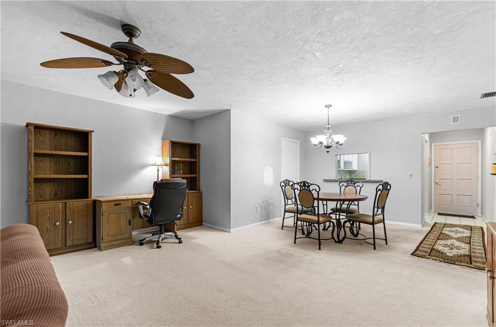 Dining area with an office area, light colored carpet, ceiling fan, a textured ceiling, and a chandelier