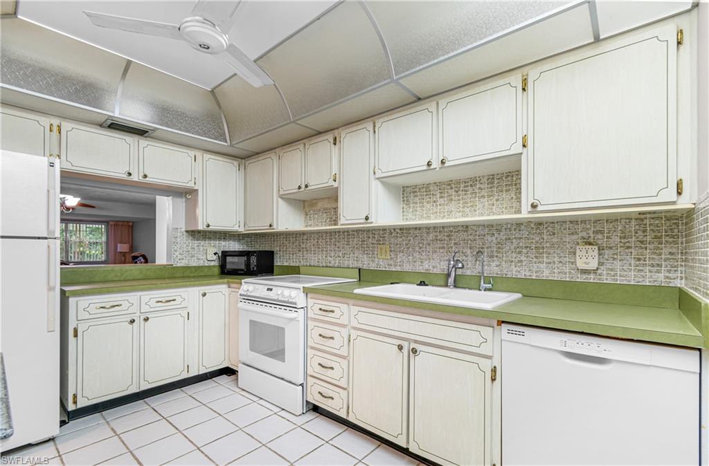 Kitchen featuring a ceiling fan, white appliances, light countertops, light tile patterned flooring, and tasteful backsplash