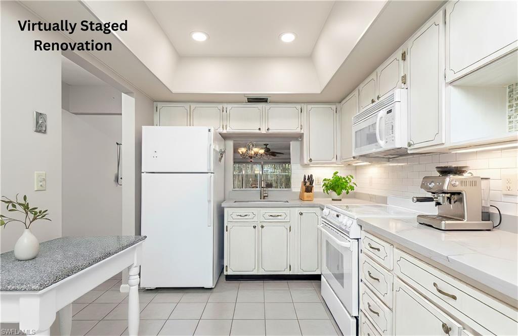Kitchen with white appliances, a raised ceiling, white cabinets, light tile patterned floors, and tasteful backsplash