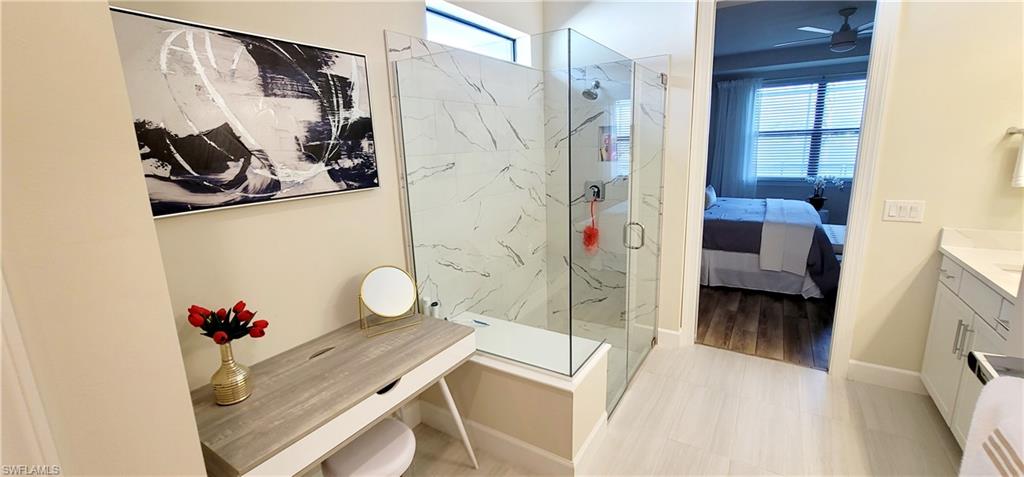 Bathroom featuring ceiling fan, a shower with shower door, and vanity