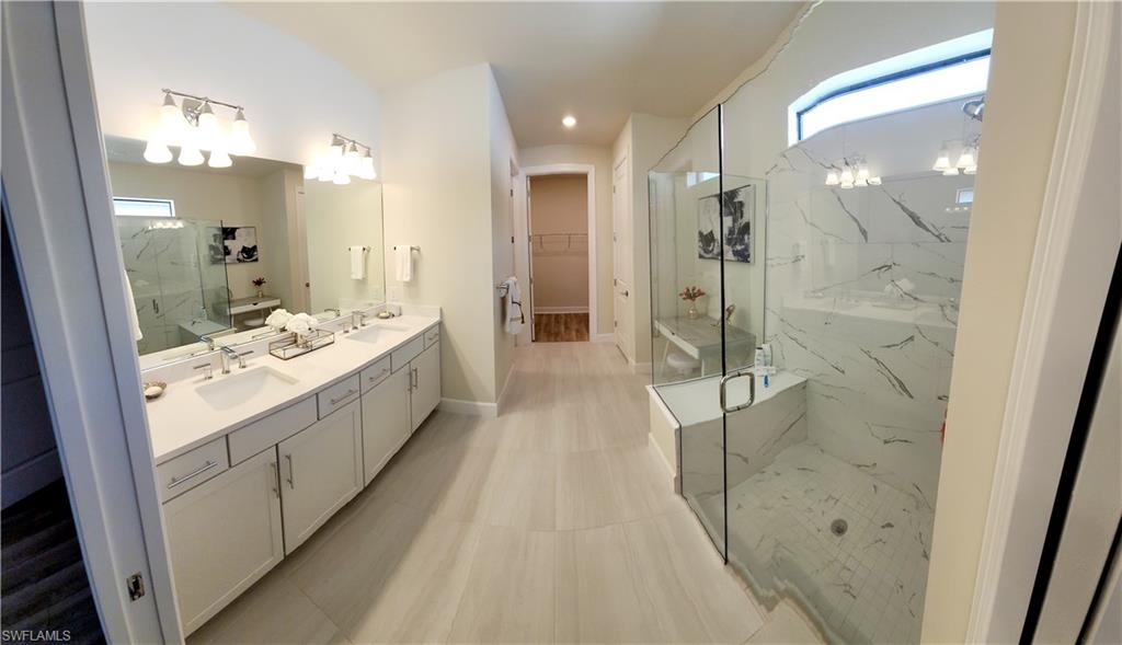 Bathroom featuring vanity, a shower with door, and a healthy amount of sunlight