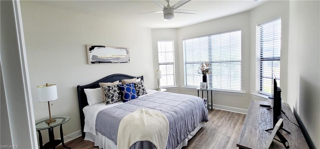 Bedroom with light wood-type flooring, multiple windows, and ceiling fan