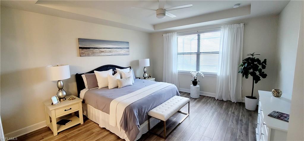 Bedroom featuring hardwood / wood-style flooring, ceiling fan, and a tray ceiling