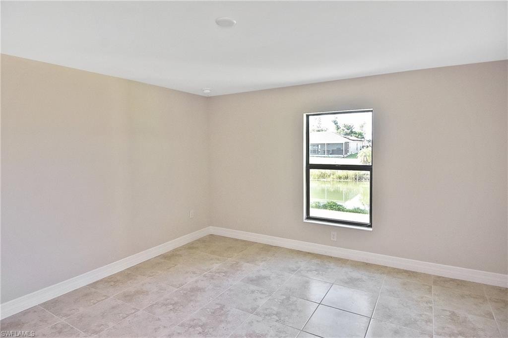 Empty room featuring baseboards and light tile patterned floors