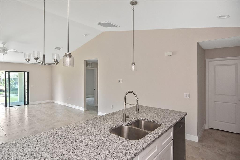 Kitchen with light tile patterned floors, white cabinets, light stone countertops, decorative light fixtures, and a ceiling fan