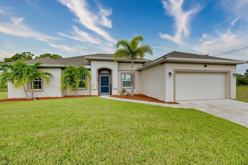 View of front of house with stucco siding, driveway, an attached garage, and a front yard