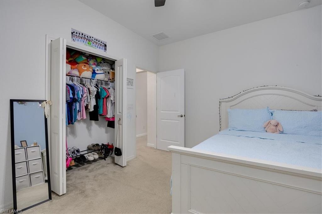Bedroom with light carpet, ceiling fan, and a closet