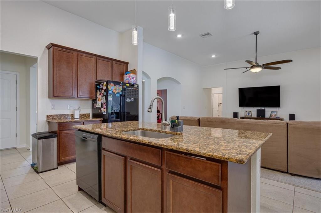 Kitchen featuring light tile patterned flooring, ceiling fan, arched walkways, black appliances, and open floor plan