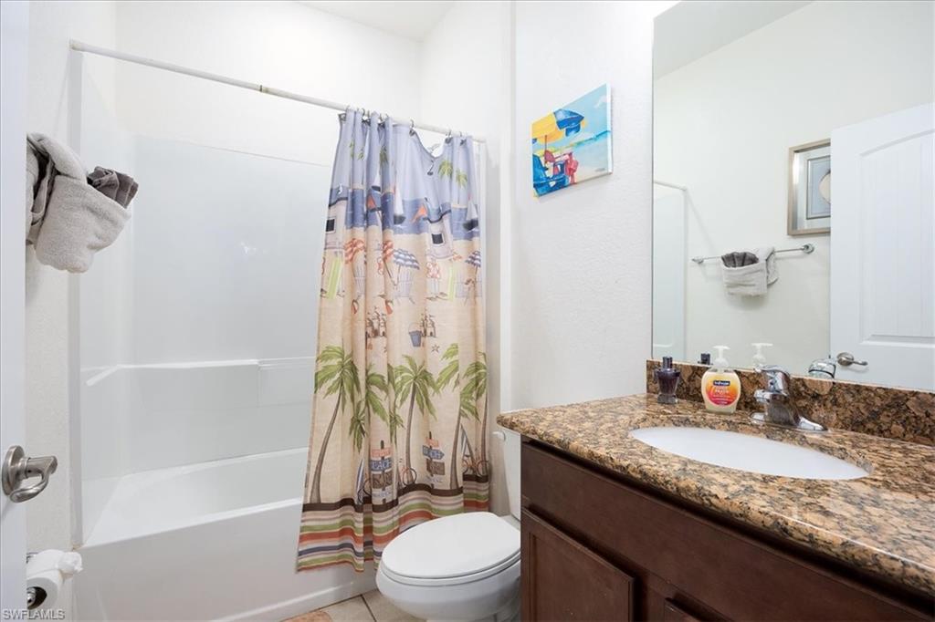 Bathroom featuring shower / bath combo with shower curtain, vanity, and light tile patterned floors