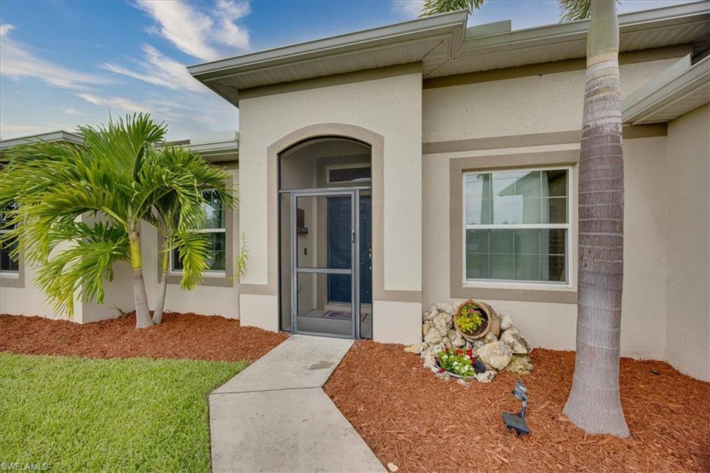 View of exterior entry with stucco siding and a yard