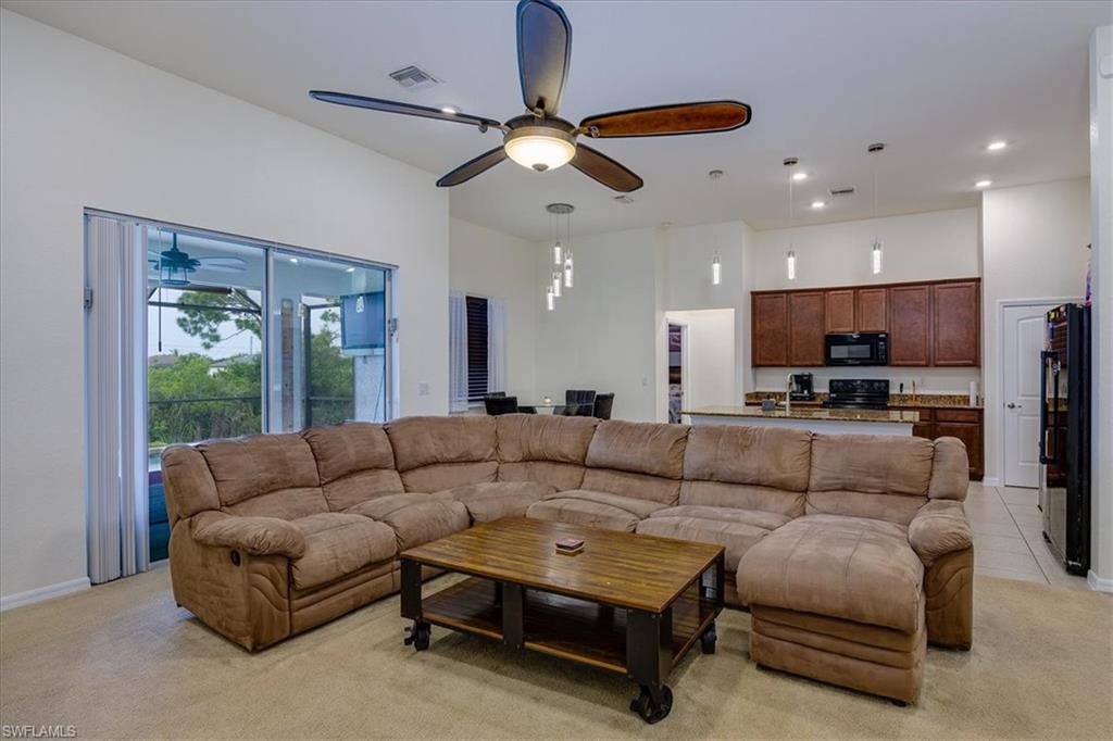 Living room with light colored carpet, ceiling fan, and recessed lighting