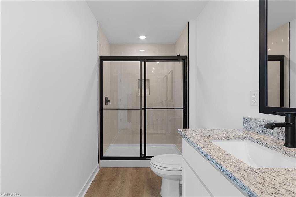 Bathroom featuring vanity, wood finished floors, and a shower stall