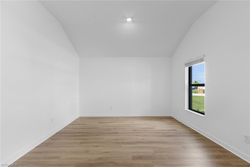 Unfurnished room with lofted ceiling and light wood-type flooring