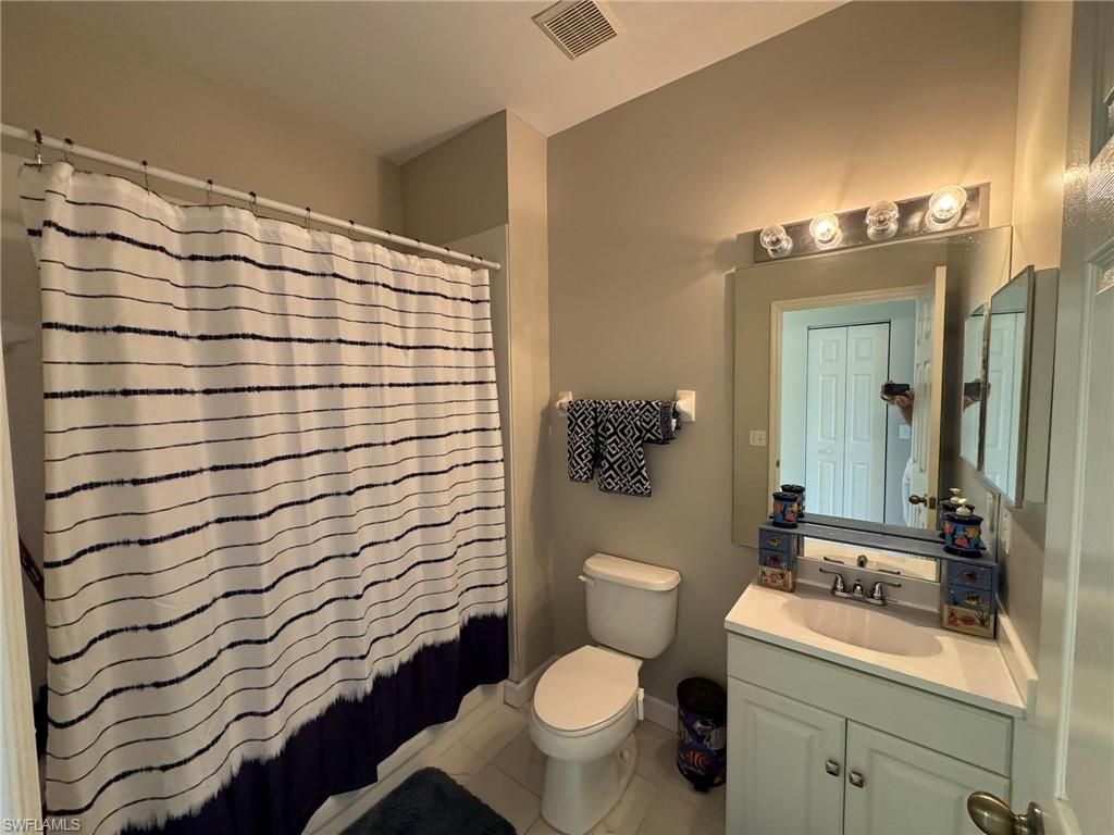 Full bathroom with shower / bath combination with curtain, tile patterned floors, vanity, and toilet