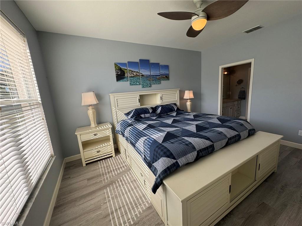 Bedroom with ceiling fan, hardwood / wood-style floors, and multiple windows