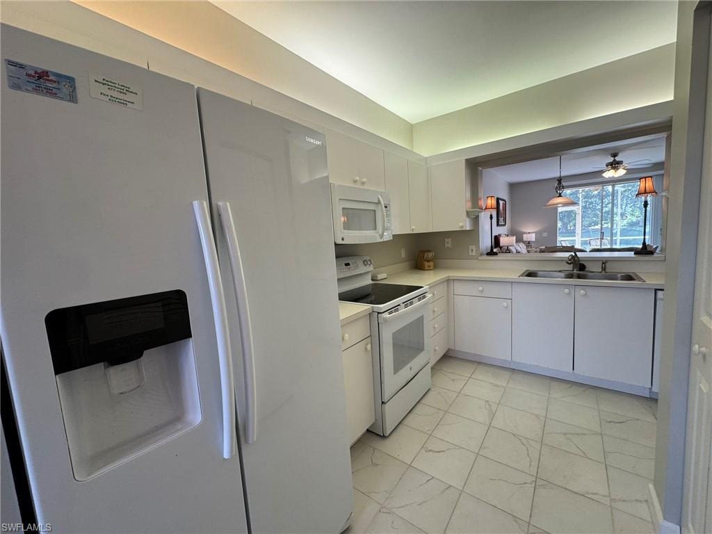Kitchen with white cabinetry, sink, white appliances, and pendant lighting