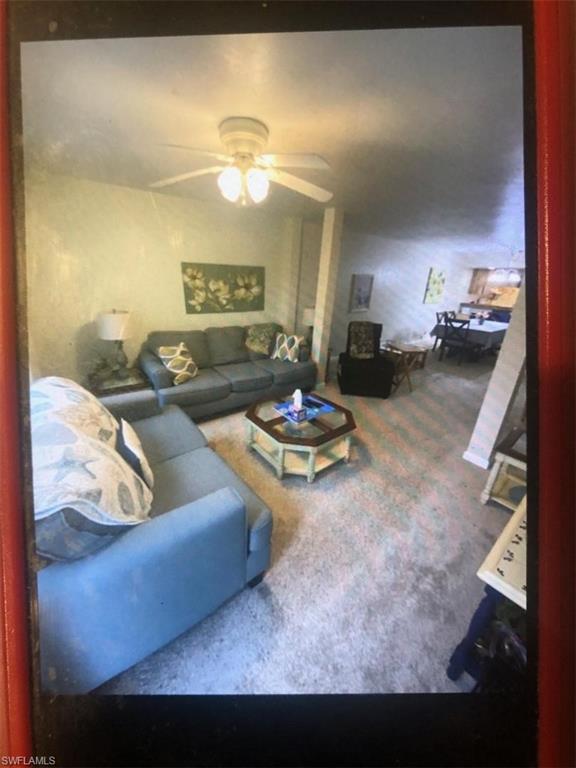 Carpeted living area featuring ceiling fan