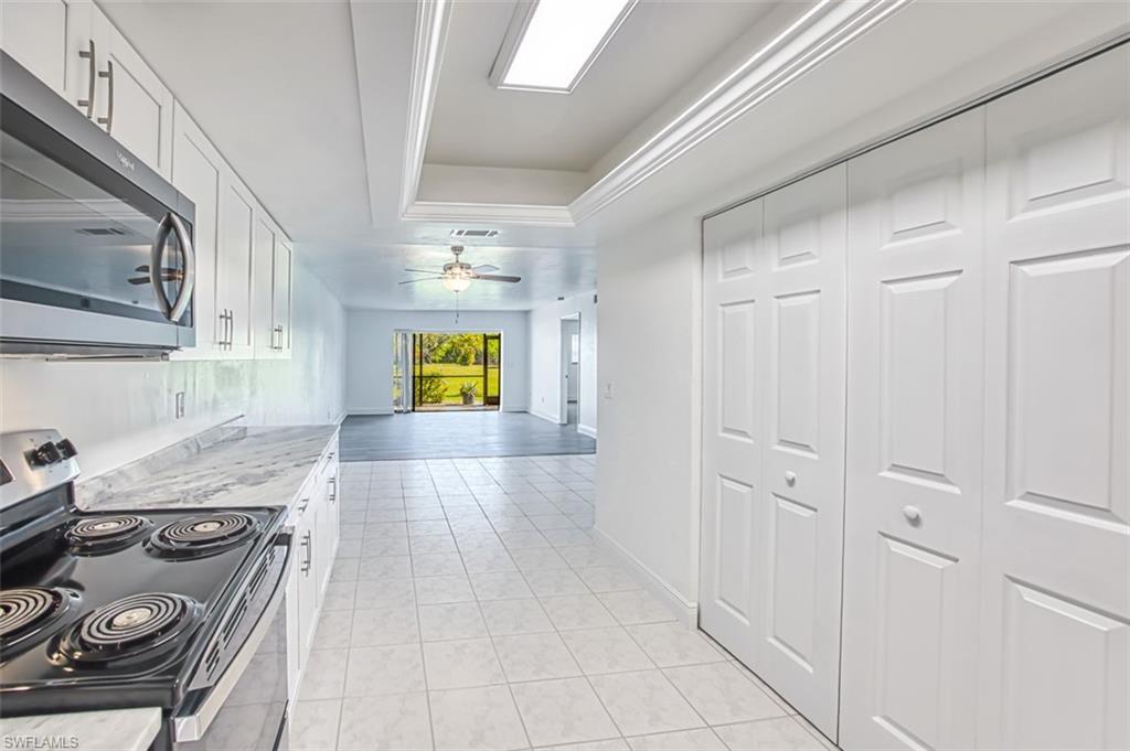 Hall featuring a tray ceiling and light tile patterned floors