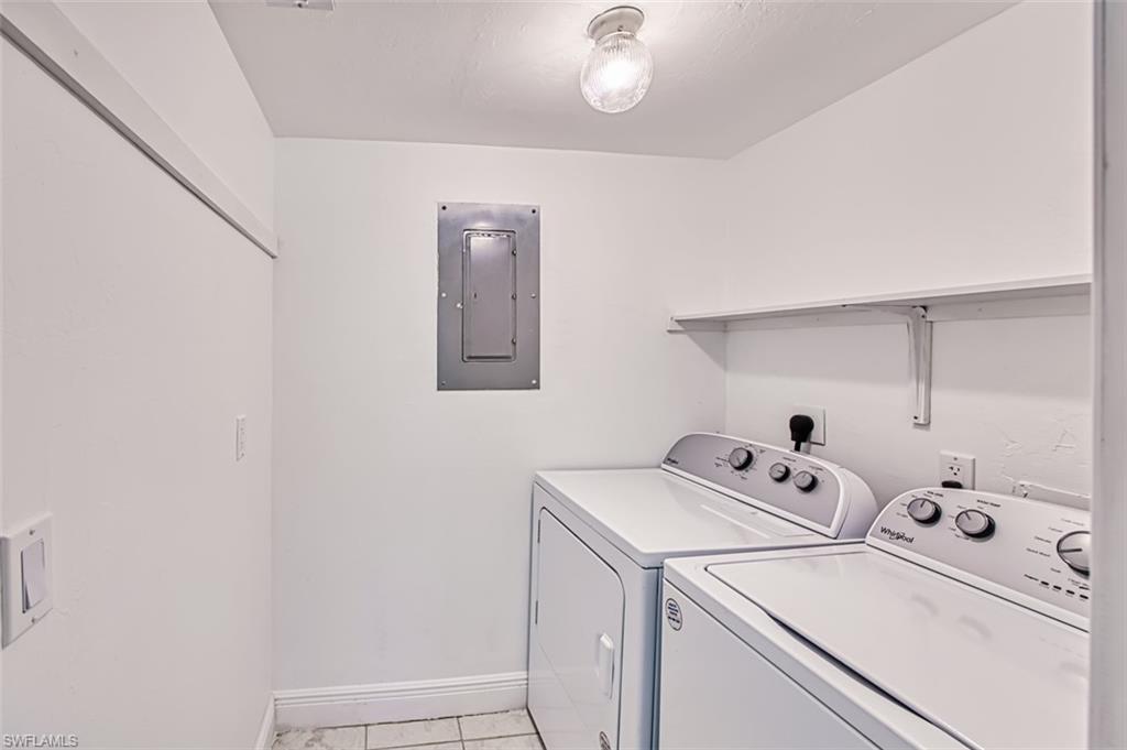 Laundry room featuring hookup for an electric dryer, electric panel, and light tile patterned flooring