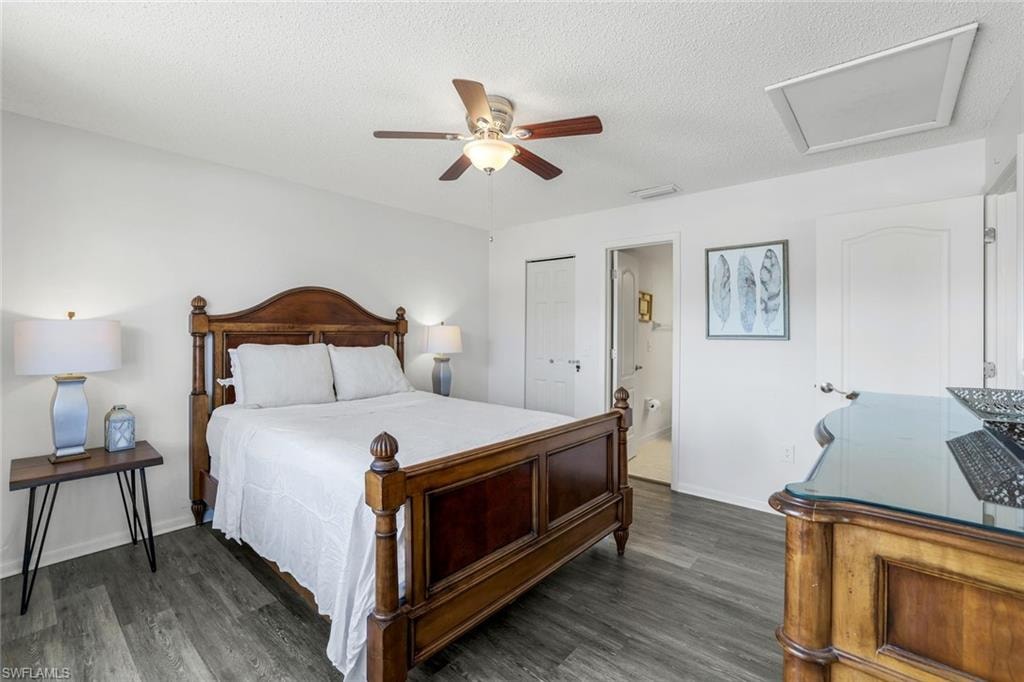 Bedroom with attic access, dark wood-style flooring, a ceiling fan, a textured ceiling, and a closet