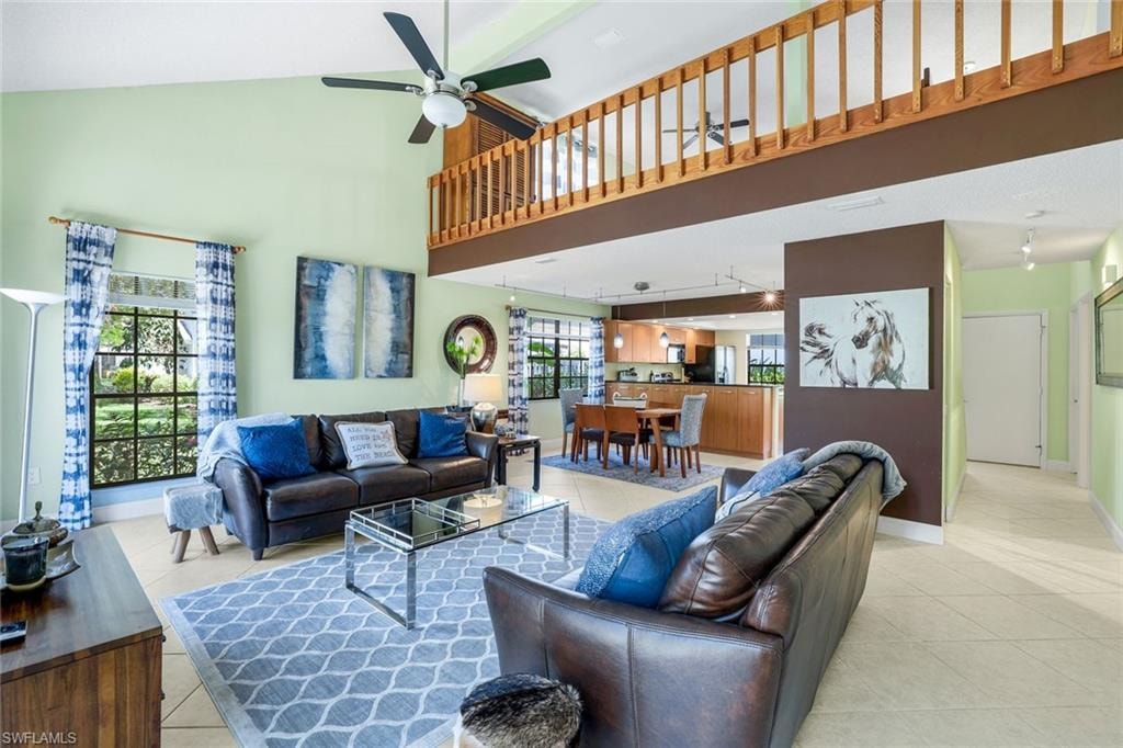 Living area featuring high vaulted ceiling, light tile patterned floors, and a ceiling fan