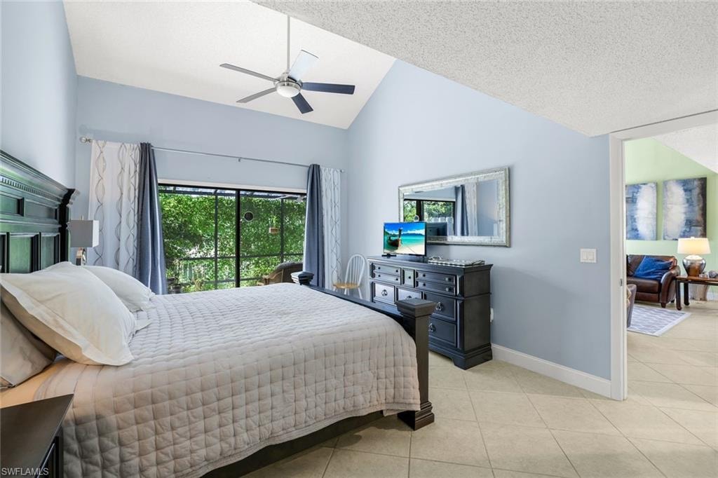 Bedroom with lofted ceiling, light tile patterned flooring, ceiling fan, and a textured ceiling